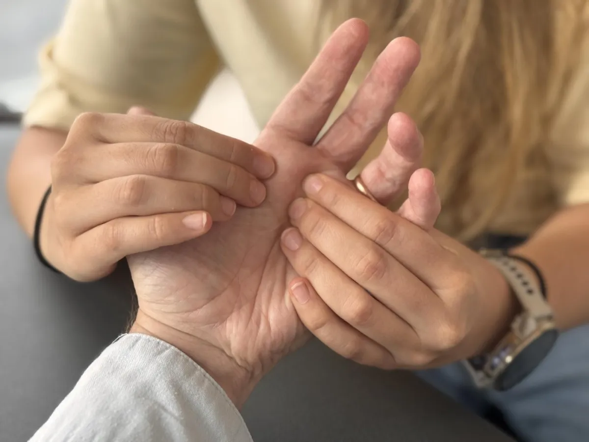 Mobilisation de la main d'une patiente par une physiothérapeute au cabinet